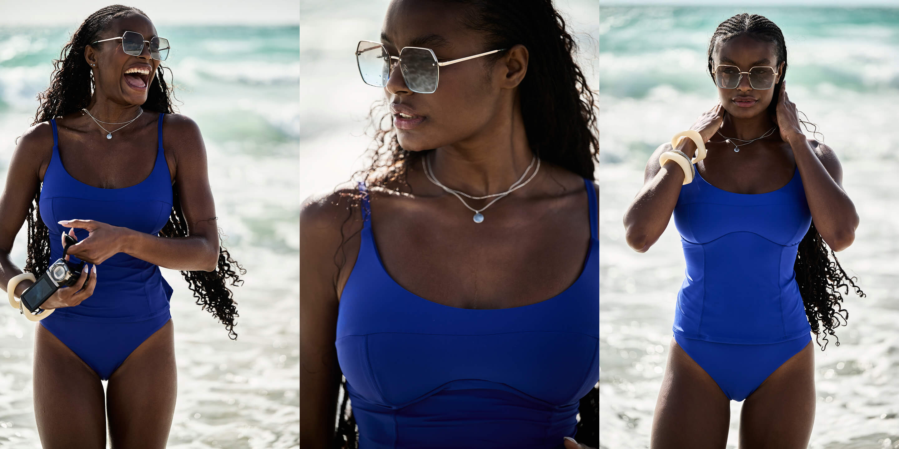 A woman in a blue swimsuit smiles while holding a camera at the beach.