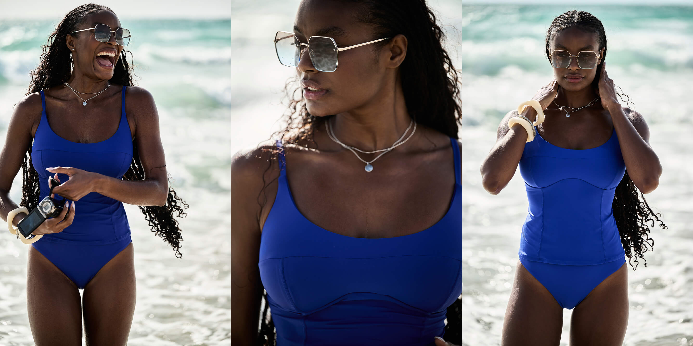 A woman in a blue swimsuit smiles while holding a camera at the beach.